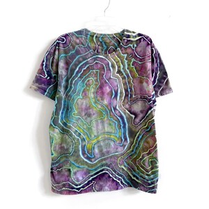 May include: A tie-dye t-shirt with a swirling pattern of purple, green, and blue colors. The shirt has a v-neck and short sleeves.
