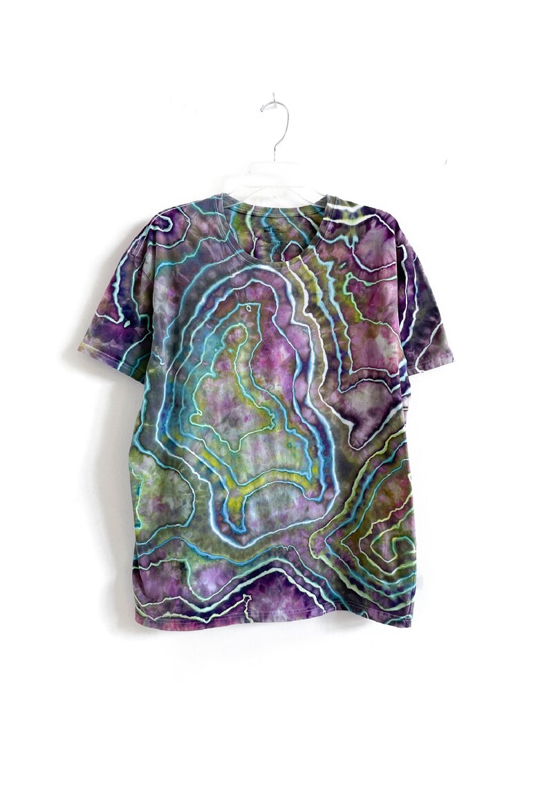 May include: A tie-dye t-shirt with a swirling pattern of purple, green, and blue colors. The shirt has a v-neck and short sleeves.