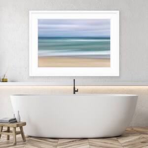 May include: A white bathtub with a black faucet in a modern bathroom with a framed abstract seascape painting above it.