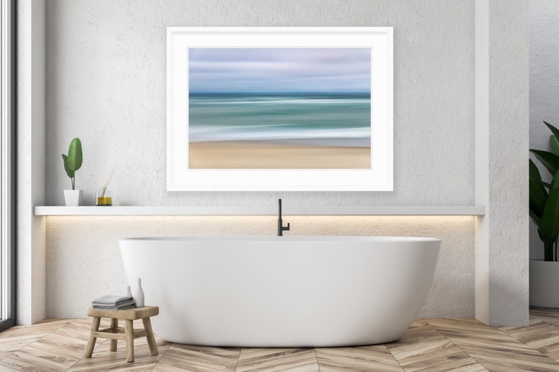 May include: A white bathtub with a black faucet in a modern bathroom with a framed abstract seascape painting above it.
