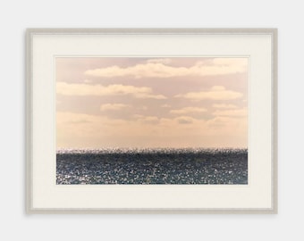 May include: A framed photograph of a seascape with a horizon line and a cloudy sky. The water is a dark blue with a shimmery, reflective surface.