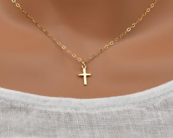 May include: A delicate gold chain necklace with a small, simple cross pendant.