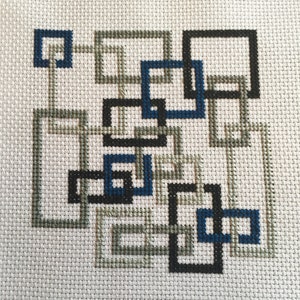 May include: A cross-stitch pattern with a geometric design featuring interlocking squares in black, gray, and blue.