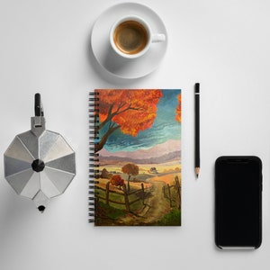 May include: A spiral bound notebook with a colorful painting of a fall landscape. The painting features a large tree with orange and red leaves, a winding path, and a small house in the distance.