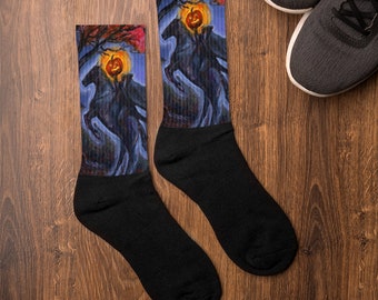 May include: A pair of black crew socks with a colorful illustration of a jack-o-lantern and two horses running through a dark forest. The socks are on a wooden surface.