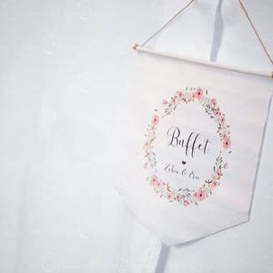 Peut inclure: Bannière blanche avec une couronne de fleurs et le texte "Buffet" en écriture cursive noire. Sous la couronne, il est écrit "Zahra & Eric" en écriture cursive noire.