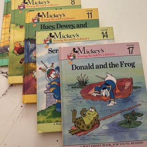 May include: A stack of five vintage Mickey Mouse children's books with colorful covers. The books are titled "Mickey's Young Readers Library" and feature different characters like Donald Duck and Huey, Dewey, and Louie. The books are numbered with volumes 2, 8, 11, 14, and 17.