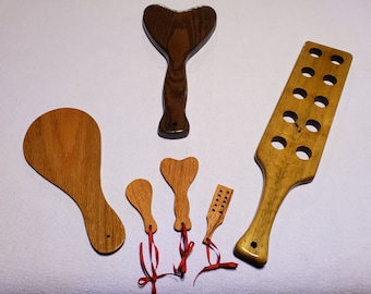 Puede incluir: Colección de herramientas de masaje de madera de varias formas. Incluye una paleta con agujeros, herramientas en forma de corazón y de lágrima, y herramientas con mangos. Algunas tienen cintas rojas.
