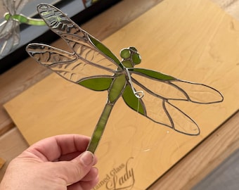 虹色に輝く緑色のステンドグラスで作られた立体的なトンボ。ユニークな