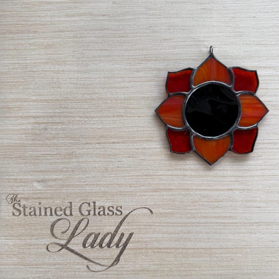 A hand-soldered stained glass mini sunflower suncatcher in a striking red-orange colorway — actual leaded glass craft, not a print, and 41 favorites proves people want it.