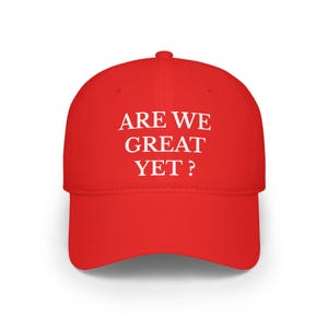 Op de afbeelding: Rode baseballpet met witte tekst die "ARE WE GREAT YET?" zegt.