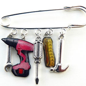 Stecknadel für Bastelmaschinen, rosa Bohrer und Meterband, Schraubendreher, Hammer und Silbermetallschlüssel