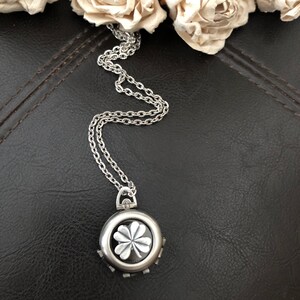 May include: A silver chain necklace with a round pendant featuring a four-leaf clover design.