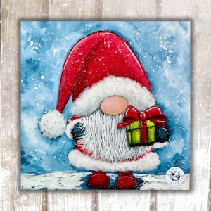 May include: A square painting of a gnome wearing a red hat with white trim and a white beard, holding a green gift box with a red bow. The background is a blue sky with white snowflakes, and the gnome stands on a white snowy surface.