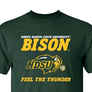 May include: A dark green t-shirt with the words "North Dakota State University" and "Bison" in yellow. The t-shirt also features a yellow bison logo with the letters "NDSU" and the text "Feel the Thunder".