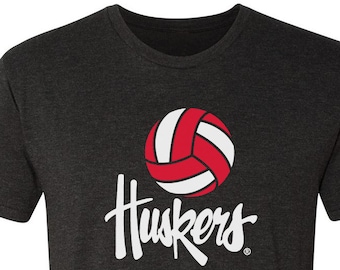 May include: A dark heather grey t-shirt with a white volleyball graphic and the text "Huskers" in white.