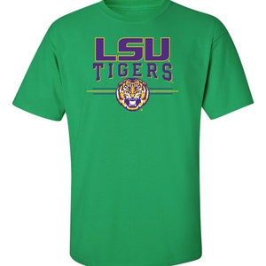 Puede incluir: Camiseta verde con el logotipo de los LSU Tigers en morado y dorado. El logotipo presenta una cabeza de tigre con el texto 'LSU' en morado y dorado encima.