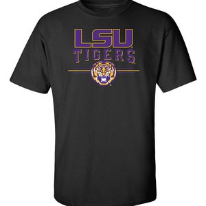 Puede incluir: Camiseta negra con un logotipo de LSU Tigers en morado y dorado y un gr&aacute;fico de cabeza de tigre.