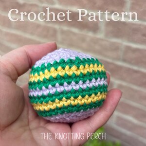 May include: A spherical crochet object featuring horizontal stripes in light purple, vibrant green, and bright yellow yarn. The text Crochet Pattern and The Knotting Perch are visible in white lettering against the background of the image.