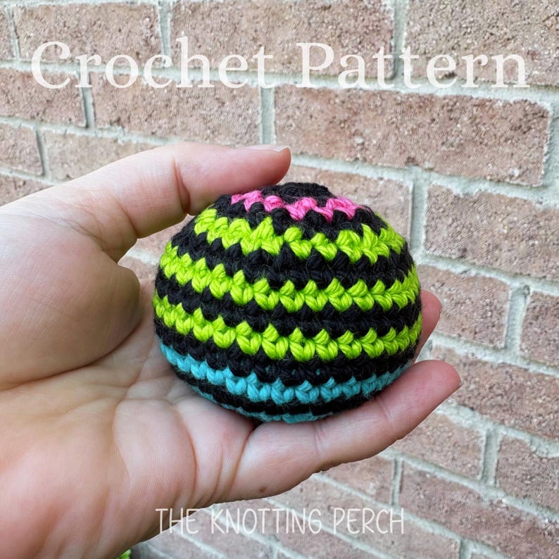 May include: A spherical crochet object featuring horizontal stripes in black, lime green, bright pink, and turquoise. The text Crochet Pattern and The Knotting Perch are visible in white lettering against the background of a brick wall.