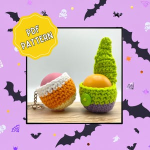 Könnte beinhalten: Zwei gehäkelte Halloween-Artikel. Einer ist ein Candy-Corn-Schlüsselanhänger, der andere ein grüner und lila Zwerg mit einer orangefarbenen Kugel. Das Bild hat ein gelbes Schild mit der Aufschrift "PDF PATTERN".