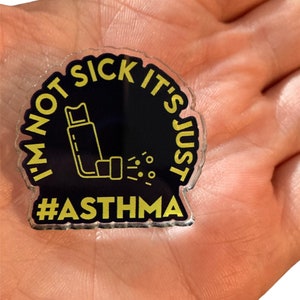 May include: A black and yellow acrylic pin with the text "I'm not sick it's just #ASTHMA" and a graphic of an inhaler.