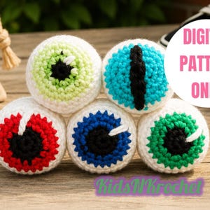 Puede incluir: Colección de cinco objetos con forma de globo ocular tejidos a ganchillo, con detalles blancos, rojos, azules y verdes. El texto "DIGITAL PATTERN ONLY" está en un círculo rosa. Sobre una superficie de madera.
