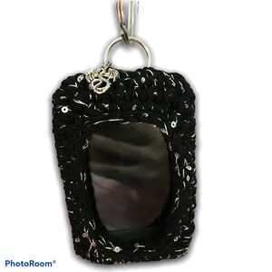 May include: Black crocheted phone case with silver sequins and a silver dragon charm attached to a silver key ring.