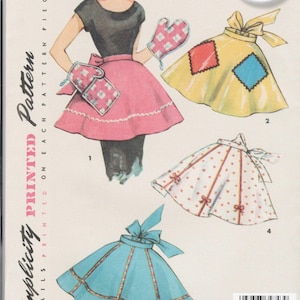 May include: Vintage Simplicity sewing pattern from the 1950s for a one-size apron. The pattern includes three different styles of aprons with various colors and patterns. The pattern is labeled "Simplicity Printed Pattern" and "Authentic Original Pattern".