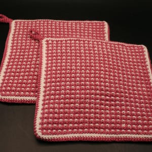 May include: Two pink and white crocheted pot holders with a textured design.