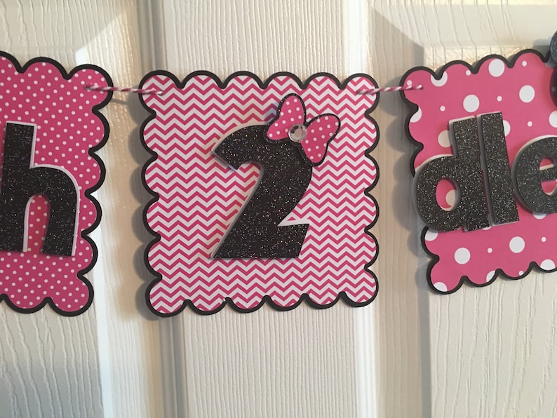 May include: Pink and black birthday banner with the words "Happy 2nd Birthday". The banner has a chevron pattern, polka dots, and a black bow with a rhinestone.