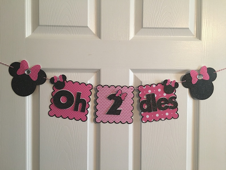 May include: Pink and black Minnie Mouse themed birthday banner with the text "Oh 2 dles".