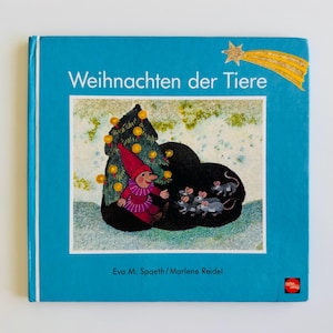 May include: A children's book titled "Weihnachten der Tiere" with a blue cover. The illustration features a gnome in a red hat and outfit, a decorated Christmas tree, and several mice. A gold star with a tail is in the upper right corner.
