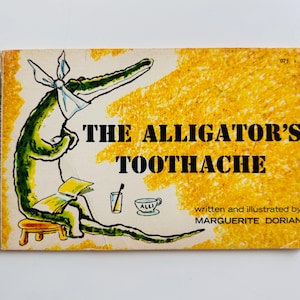 May include: Vintage children's book cover titled "The Alligator's Toothache." The illustration features a green alligator with a bandage on its head, sitting on a stool, reading a book. The background is yellow with a textured pattern.