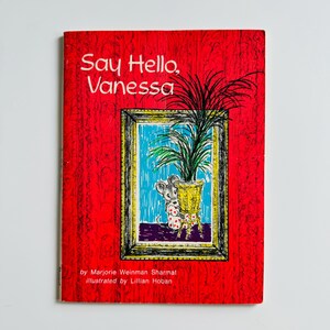 Op de afbeelding: Een rode boekomslag met de titel "Say Hello, Vanessa" in witte tekst. De omslag toont een illustratie van een muis die uit een potplant in een fotolijstje kijkt.