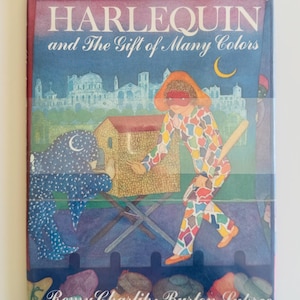 May include: A book cover titled "HARLEQUIN and The Gift of Many Colors" with illustrations. The cover features a harlequin figure in colorful patchwork clothing, a building, and a crescent moon against a blue sky. The authors' names are at the bottom.