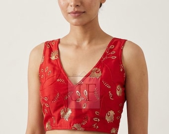May include: A sleeveless red blouse featuring a deep V-neckline and intricate gold-toned embroidery patterns across the front. The garment is cropped at the waist and includes a semi-transparent logo overlay with the letters JP centred on the chest.