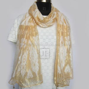 May include: A gold and white scarf with a floral pattern is draped over a white shirt on a mannequin. The scarf has a sheer, flowing texture and is adorned with tassels at the ends. The text "JahanviFashionShop.etsy.com" is visible on the shirt.