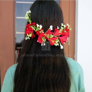 May include: A floral hair accessory featuring vibrant red flowers and delicate white accents. The design is arranged across the hair, creating a decorative and eye-catching look. The text "JahanviFashionShop.etsy.com" is visible.