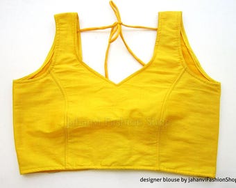 May include: A bright yellow sleeveless blouse with a V-neck and a tie at the back. The blouse is made of a soft, lightweight fabric.