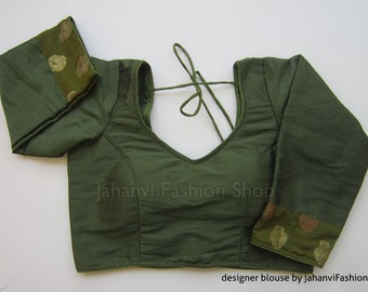 May include: Olive green blouse with long sleeves and a deep V-neck. The cuffs feature a decorative patterned trim. The blouse has a tie closure at the back. The text "Jahanvi Fashion Shop" and "designer blouse by jahanviFashionShop" are visible.