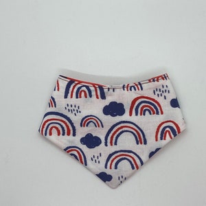 Könnte beinhalten: Ein weißes Bandana mit einem roten und blauen Regenbogenmuster. Das Bandana ist dreieckig gefaltet und hat einen weißen Hintergrund mit roten und blauen Regenbögen und Wolken.