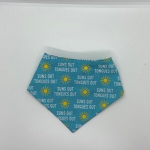 Könnte beinhalten: Ein blaues Bandana mit einem sich wiederholenden Muster aus gelben Sonnen und dem Text "Suns Out Tongues Out".