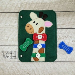 May include: A felt activity board with a giraffe design. The giraffe has a red bow tie, blue collar, and green and blue buttons. The board is green and has a white border.