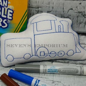 Könnte beinhalten: Ein weißer Stoffzug mit blauen Nähten, bereit zum Ausmalen mit Markern. Der Zug hat einen großen rechteckigen Wagen und einen kleineren Motorwagen mit einem Schornstein. Der Text "SEVEN'S EMPORIUM" ist auf den Zug gedruckt.