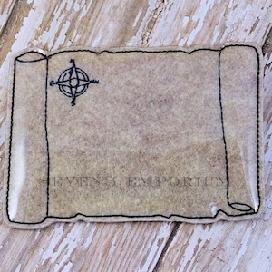 Puede incluir: Un rollo de pergamino marrón con un diseño de brújula en la esquina superior izquierda. El rollo está bordeado de negro y tiene una superficie texturizada. El texto "Stevens Emporium" es visible en la parte inferior del rollo.