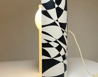 May include: A white and black geometric patterned table lamp with a white globe shade. The lamp has a white cord.