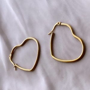 Peut inclure: Une paire de boucles d'oreilles cr&eacute;oles en forme de c&oelig;ur dor&eacute;es. Les boucles d'oreilles sont simples et &eacute;l&eacute;gantes, et seraient un excellent cadeau pour toute occasion.