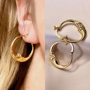 May include: Gold hoop earrings with a crescent moon design and a small clear stone accent.