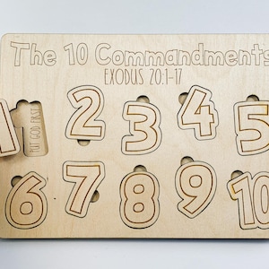 Op de afbeelding: Houten puzzel met de 10 geboden, met de tekst "The 10 Commandments EXODUS 20:1-17" en genummerde stukken van 1 tot 10.